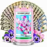 Sweet Pea Cash Money Candle with two lit wicks and a fan of cash